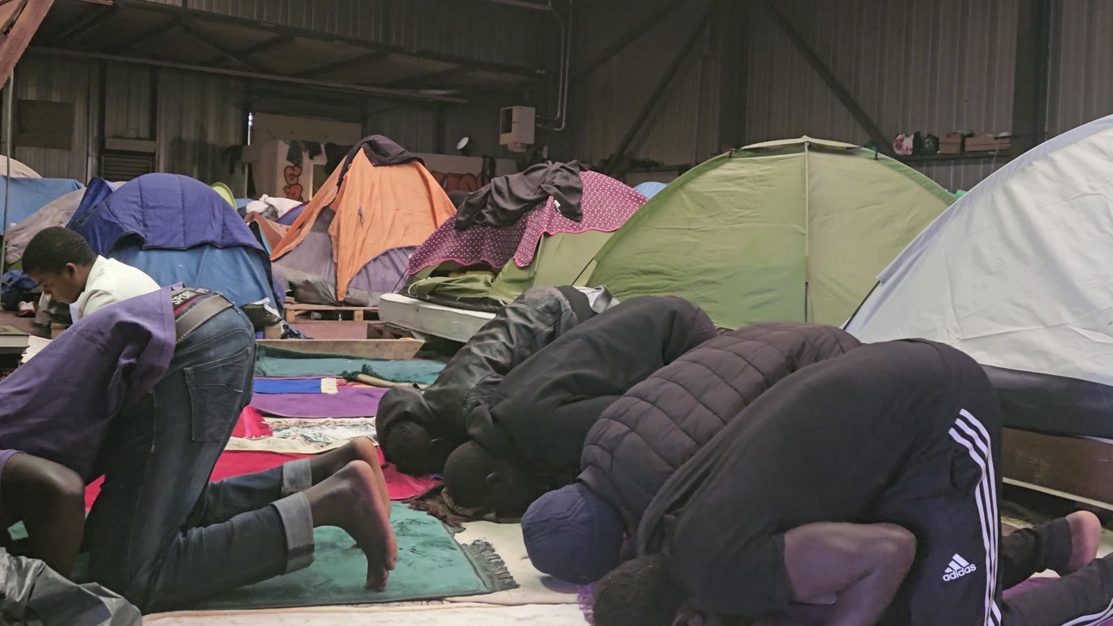 Men pray among the tents inside the camp.