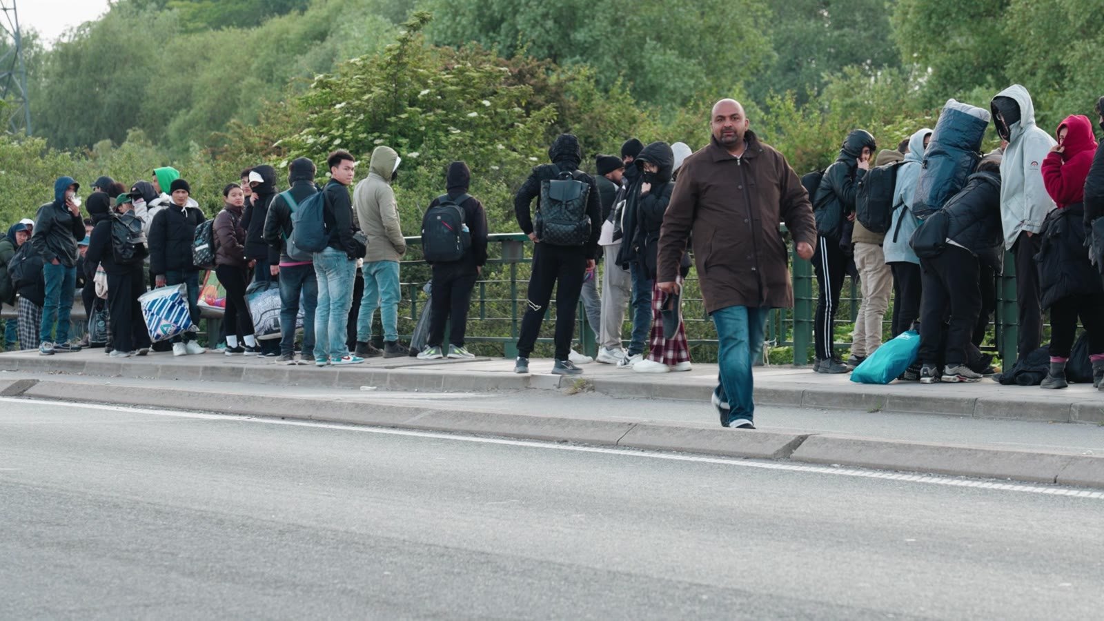 Migrants with their belongings gather at a roadside meeting point near Calais.