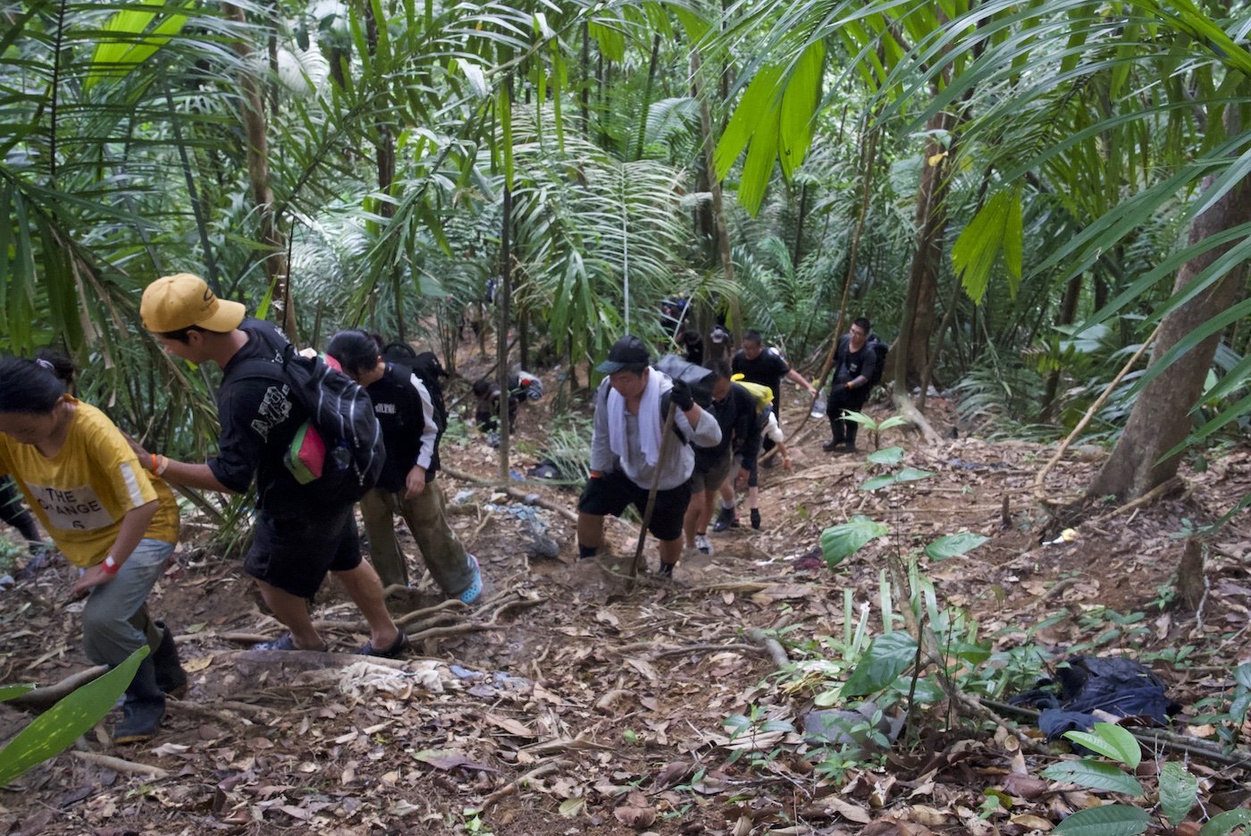 A photo of Chinese men and women climbing a hill inside the Darién Gap