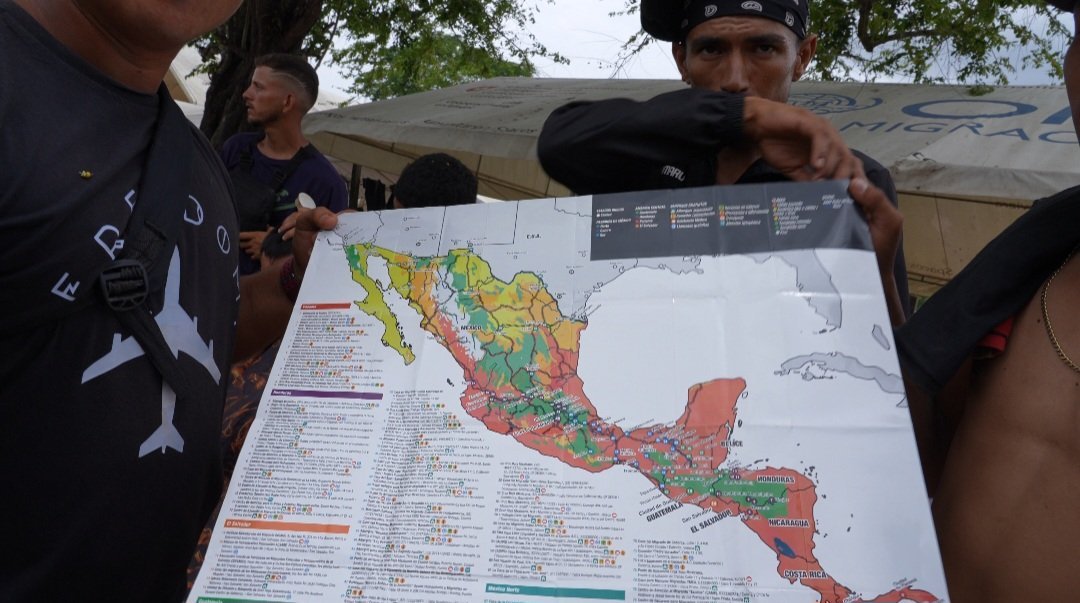 A photo of illegal aliens holding a Red Cross map at a refugee camp in the Darién Gap