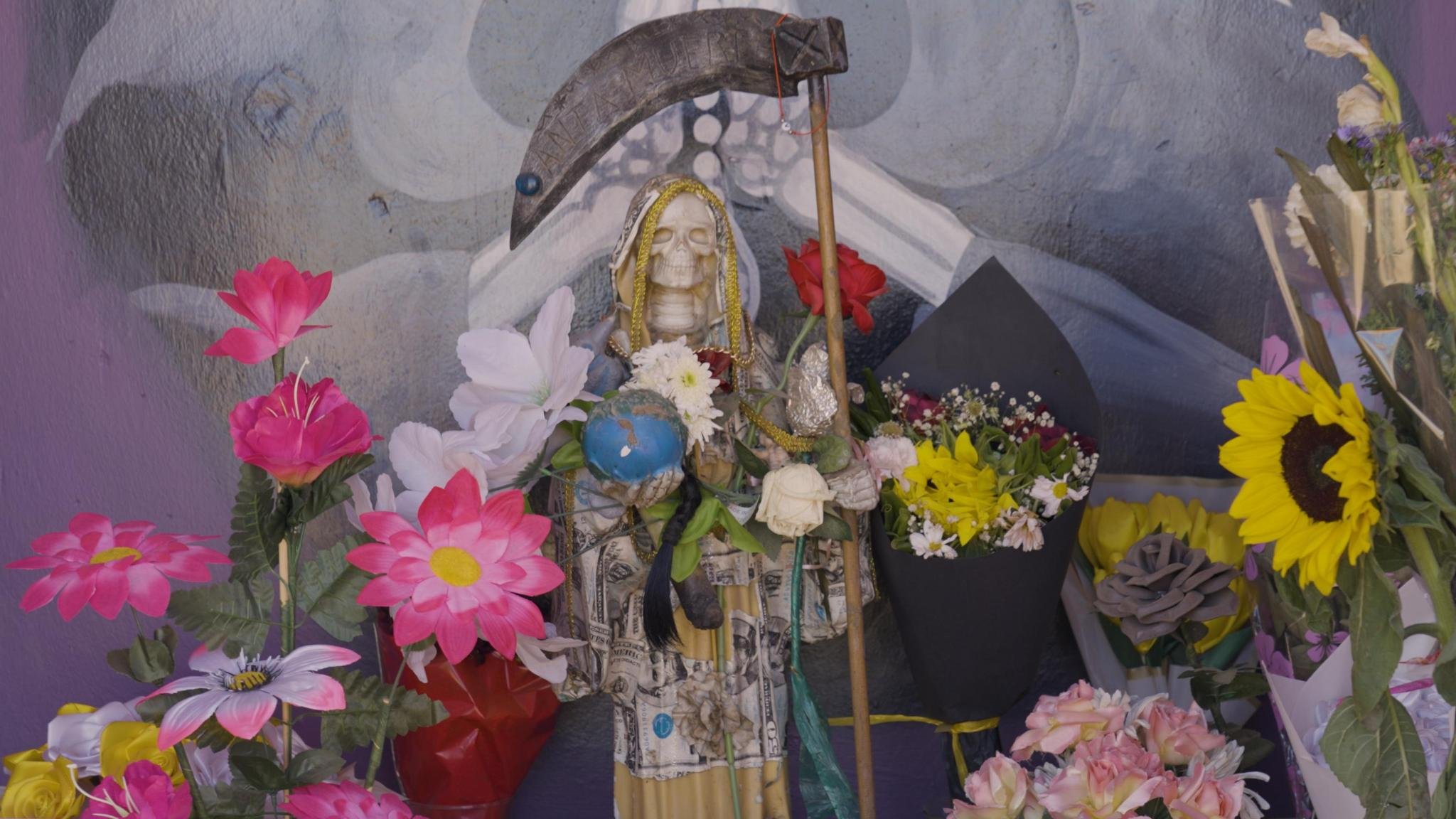 A Santa Muerte shrine with many different flowers