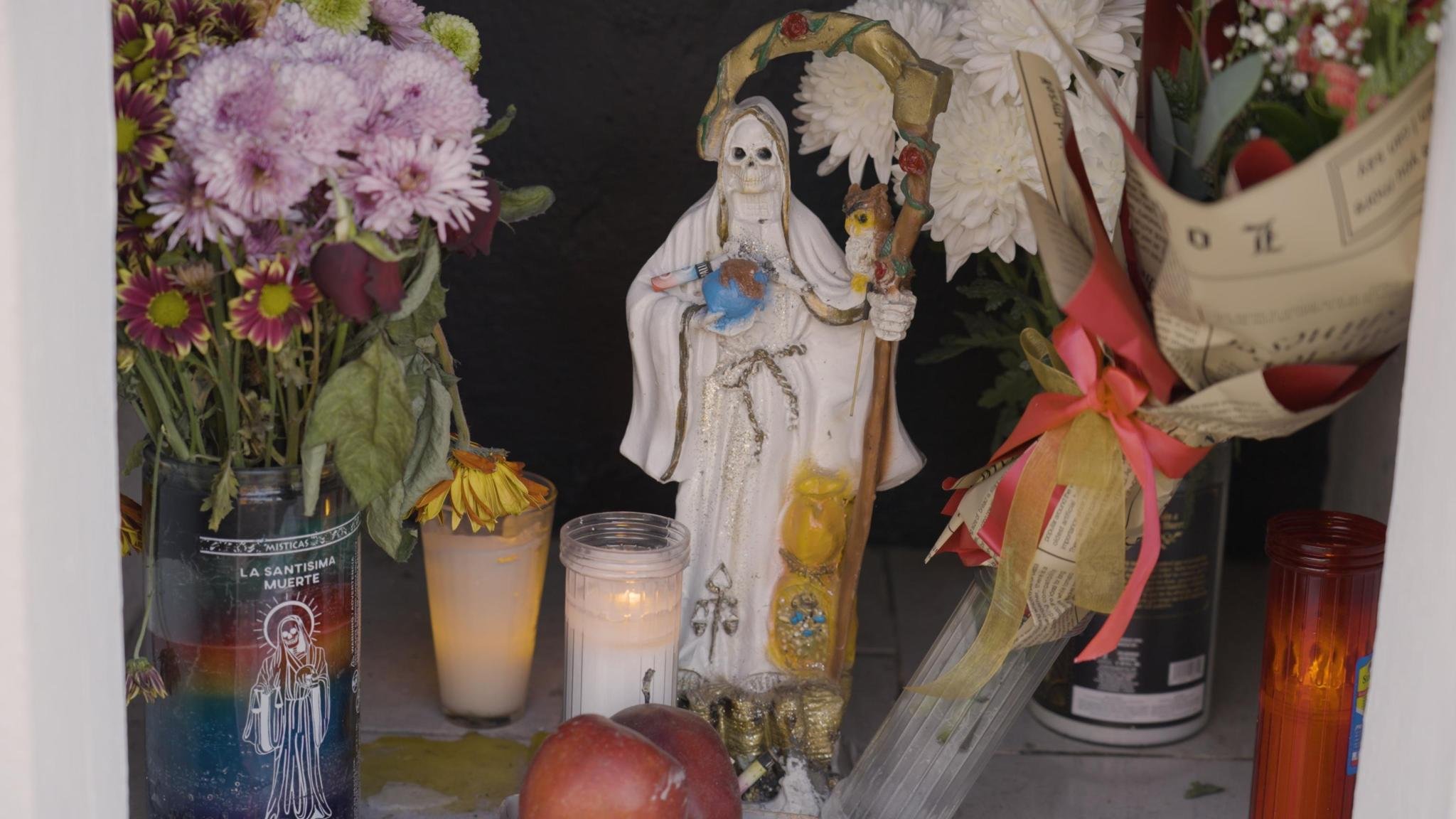 A Santa Muerte shrine with candles and offerings